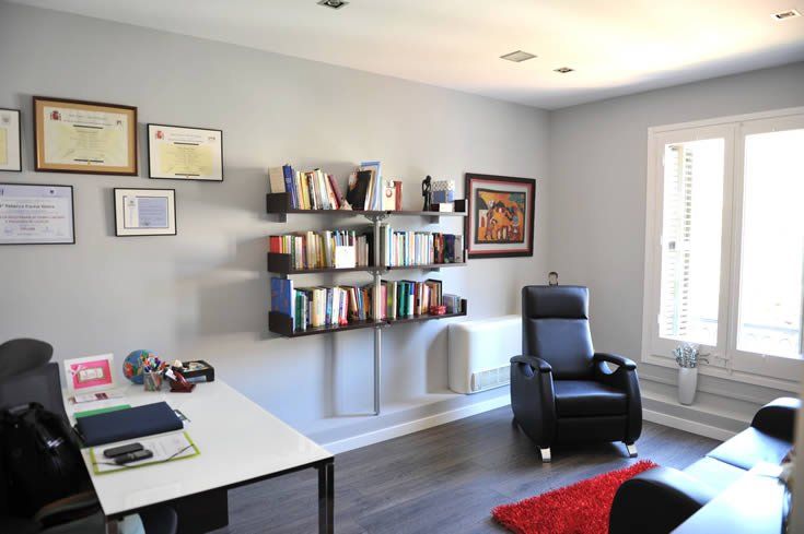Consulta de psicología con sillones, escritorio y estantería